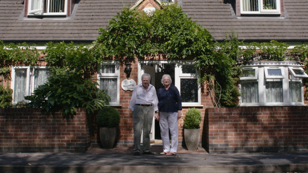Picture of David Watson with his wife standing outside the front of their house