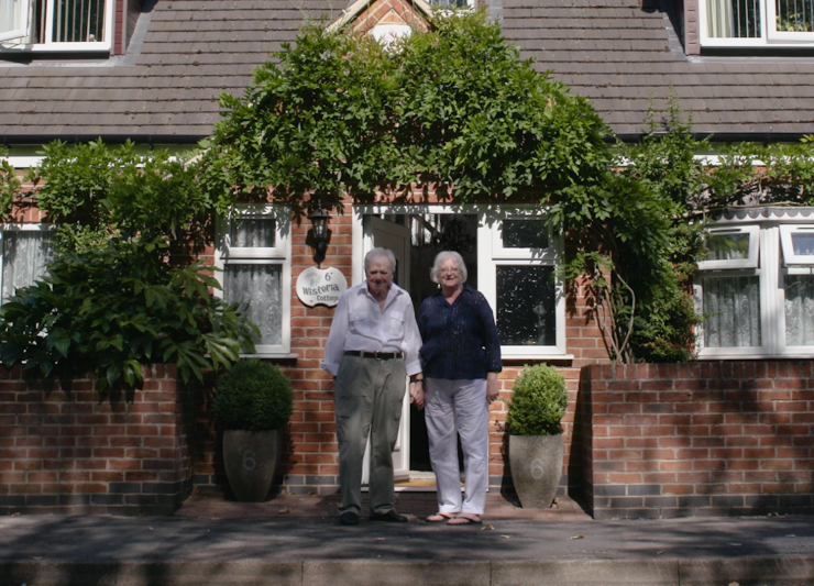Picture of David Watson with his wife standing outside the front of their house